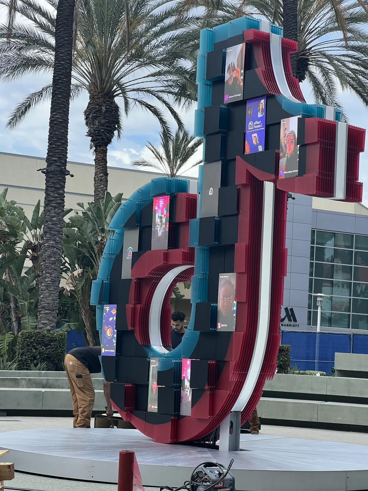 LED-clad TikTok sculpture among palms